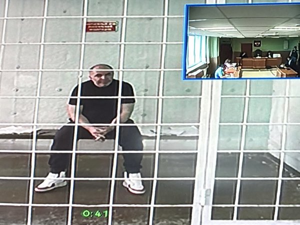 Александр Самбурский на экране телевизора. Он участвовал в заседании по видеоконференцсвязи из клетки в СИЗО. Фото 1743.ru