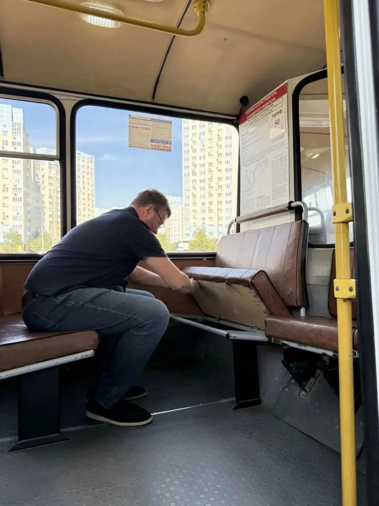 водитель закрепляет сиденье автобуса