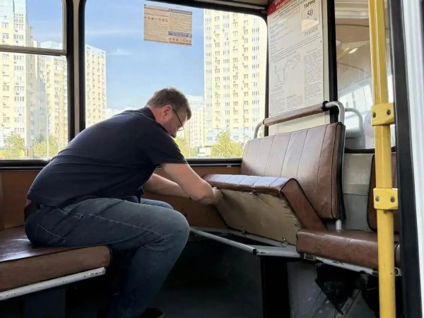 водитель закрепляет сиденье автобуса